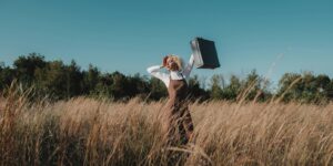 Sustainable travel: photo of a woman with suitcase in wild field
